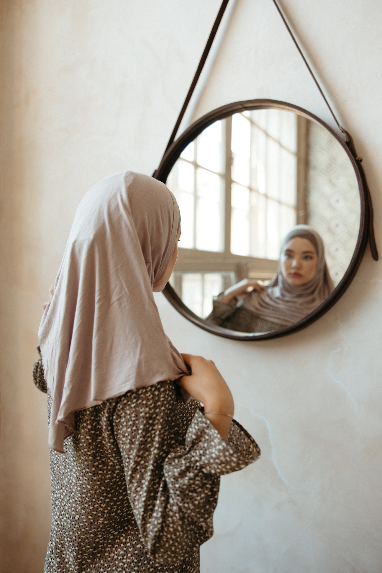 Woman in Beige Hijab Looking at a Wall Mirror