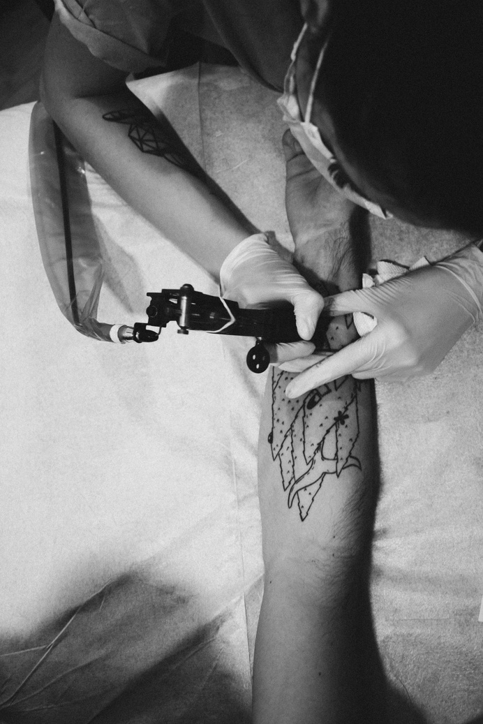 Man Holding Tattoo Machine And Tattooing Person Arm